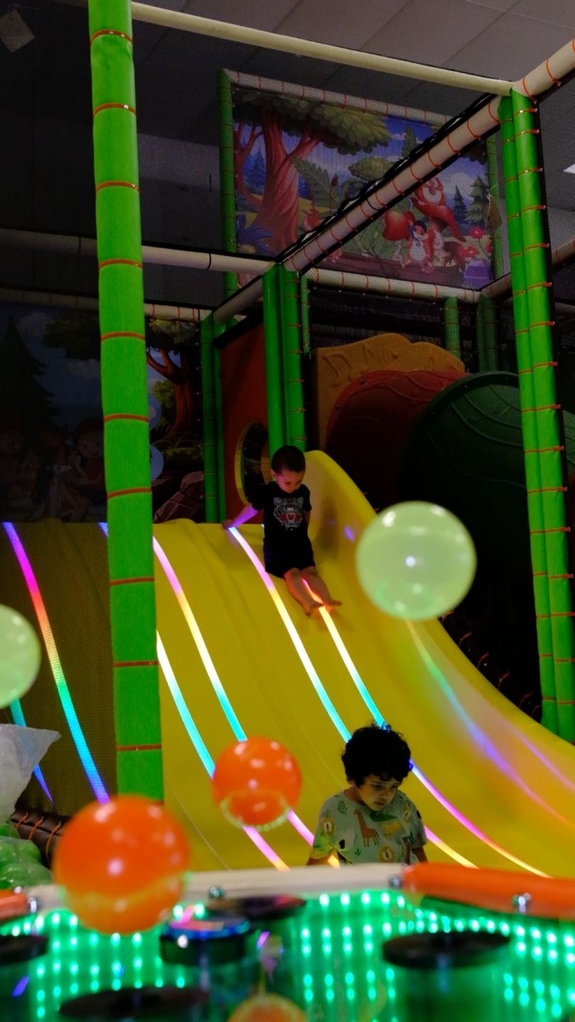 Enfants qui descendent le toboggan lumineux du parc 123 Soleil Kid's pendant les jeux libres